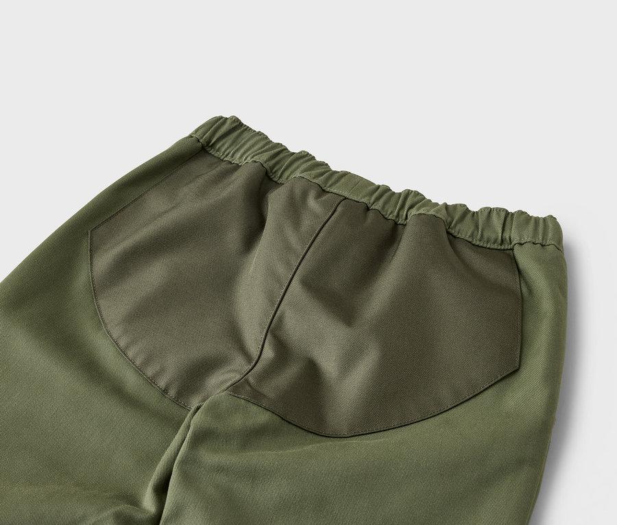 Nahaufnahme der Rückseite einer grünen Hose mit Gummibund und aufgesetzten Taschen.