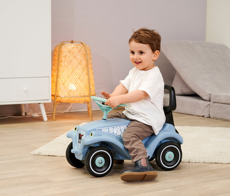 Kleiner Junge sitzt auf einem blauen BIG Bobby Car Classic Bundle mit Walker und lenkt.