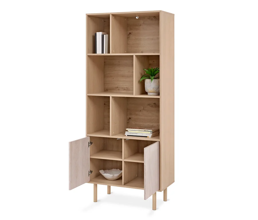 Helles Holzregal mit offenen Fächern und zwei geöffneten Türen unten, gefüllt mit Büchern, einer Pflanze und einer Schale.