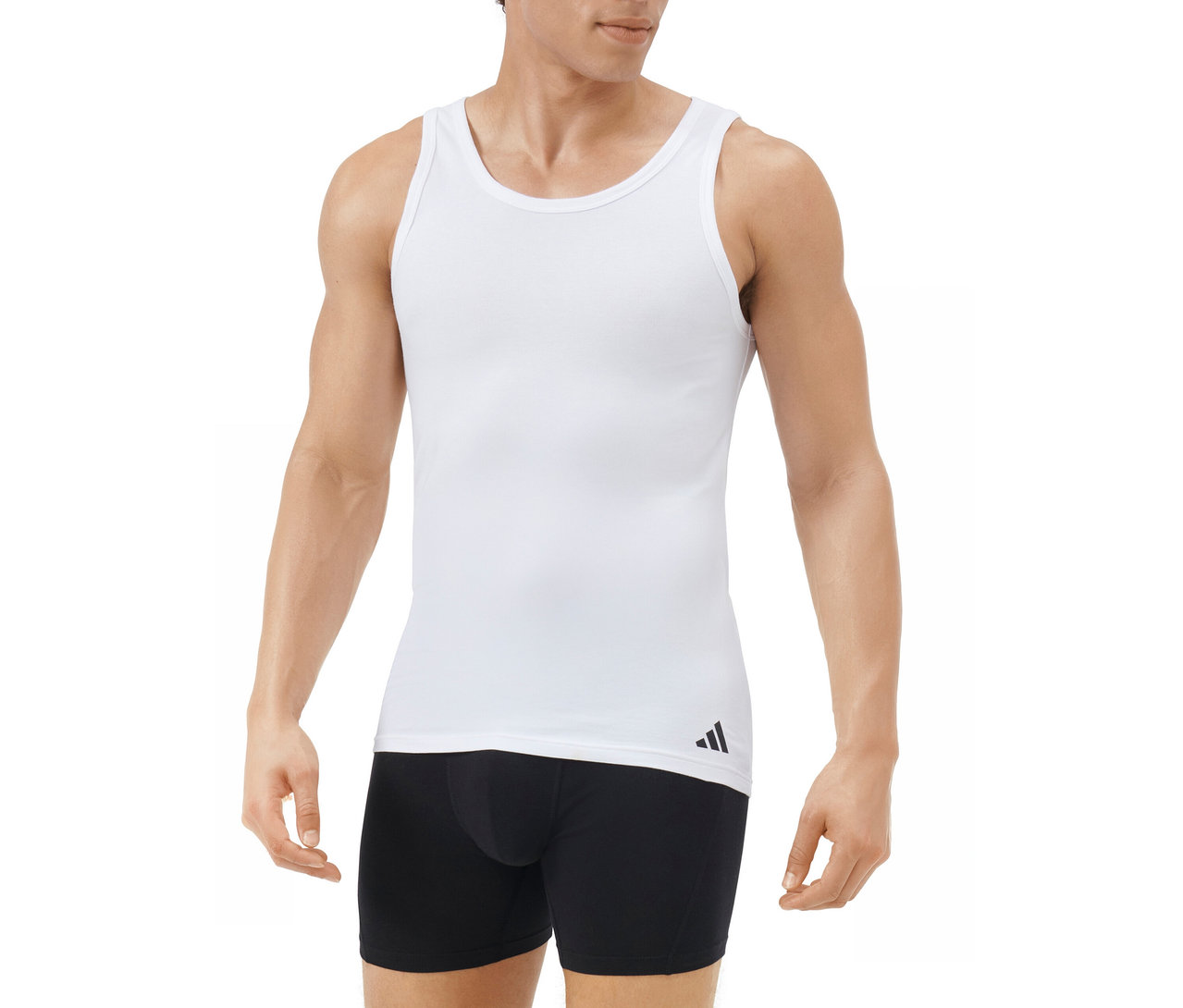 Mann trägt ein weißes Tanktop mit schwarzem Adidas-Logo am linken Saum und schwarze Boxershorts vor weißem Hintergrund.