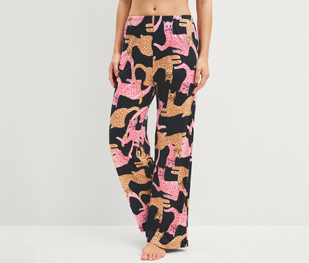 Frau trägt schwarze Hose mit rosa und braunen Katzenmustern.