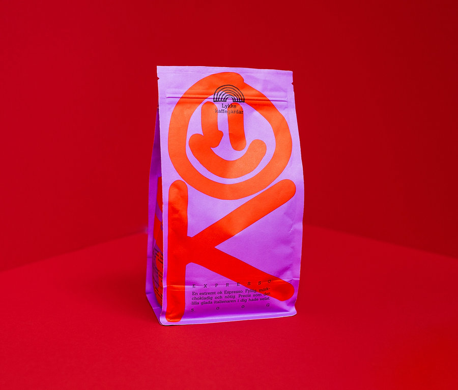 Eine lila Kaffeebohnenpackung mit orangefarbenem Aufdruck steht vor einem roten Hintergrund.