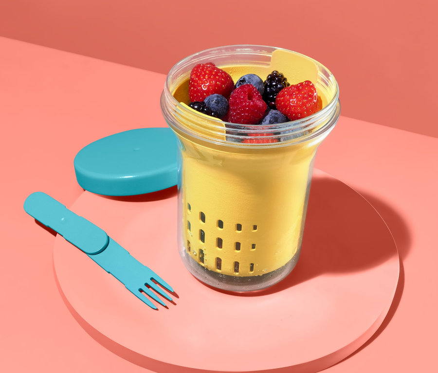 Obst in Früchte- und Salat-Box mit blauer Gabel und Deckel.