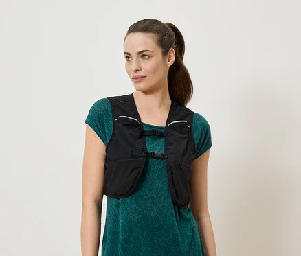 Frau trägt eine schwarze Laufweste über einem grünen Kleid.