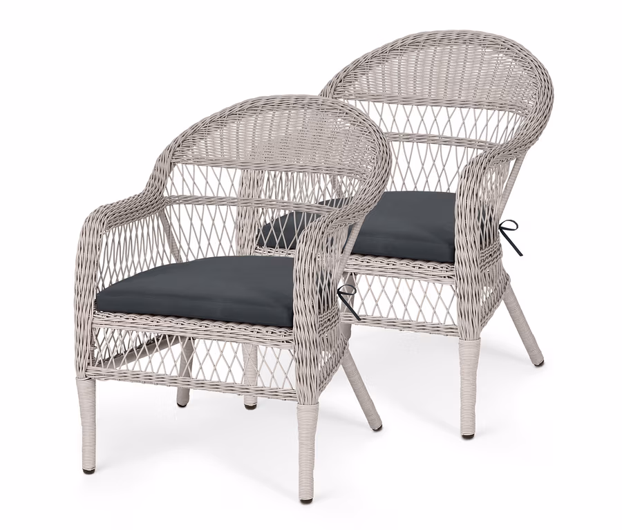 Zwei Gartensessel aus Polyrattan mit dunklen Sitzkissen.