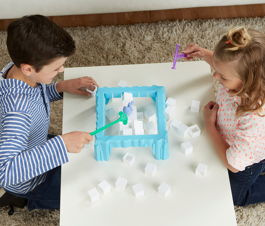 Ein Junge und ein Mädchen spielen das Spiel Hasbro »Kristallica« mit Hämmern und weißen Blöcken auf einem weißen Tisch.