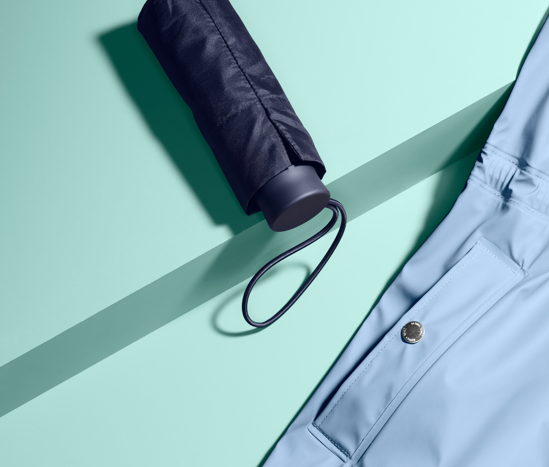 Ein Mini-Regenschirm liegt neben einer hellblauen Jacke.