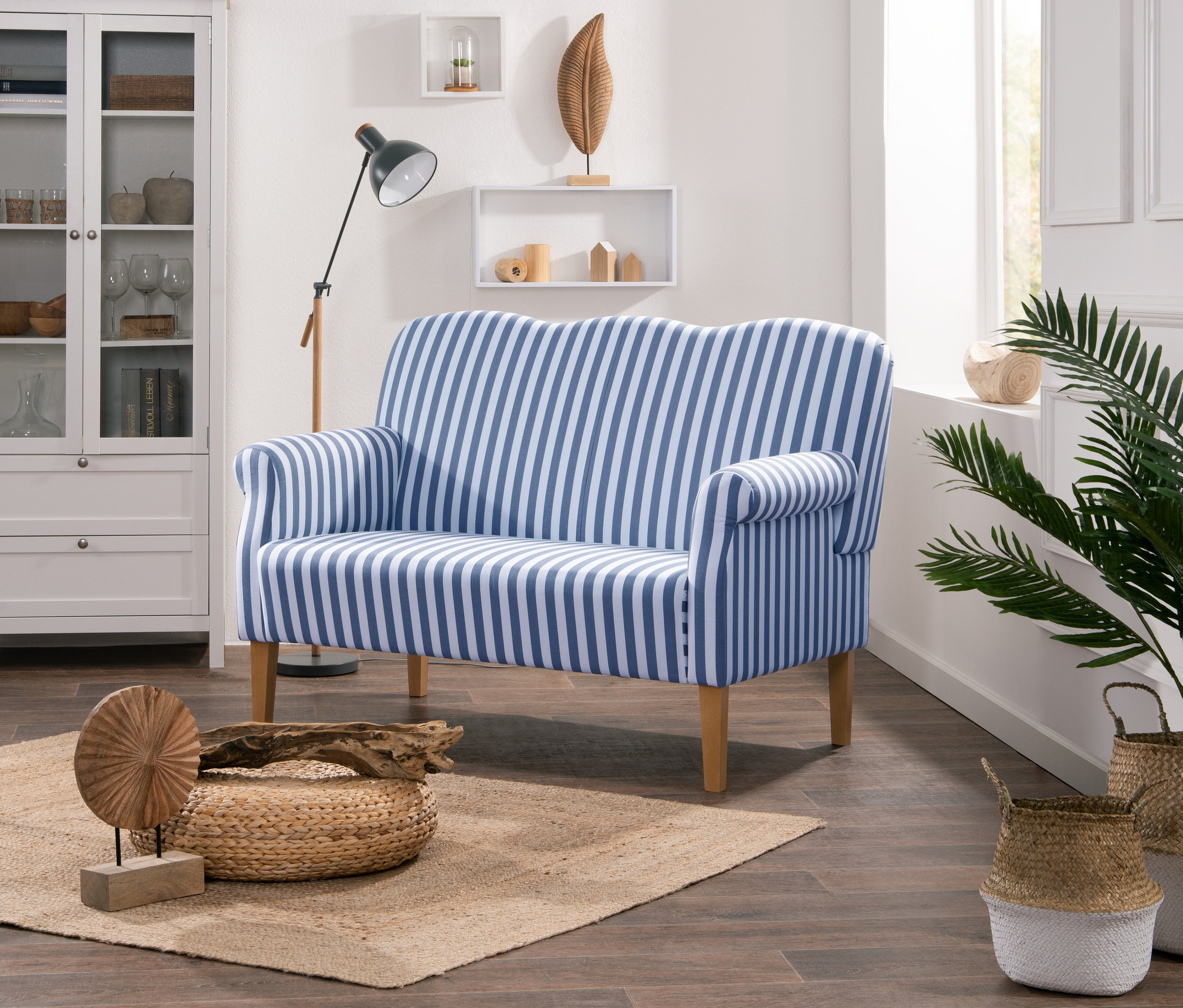 Wohnzimmer mit Möbeln und Dekorationen. Im Vordergrund befindet sich ein Küchensofa "Juuma" mit blauen und weißen Streifen.