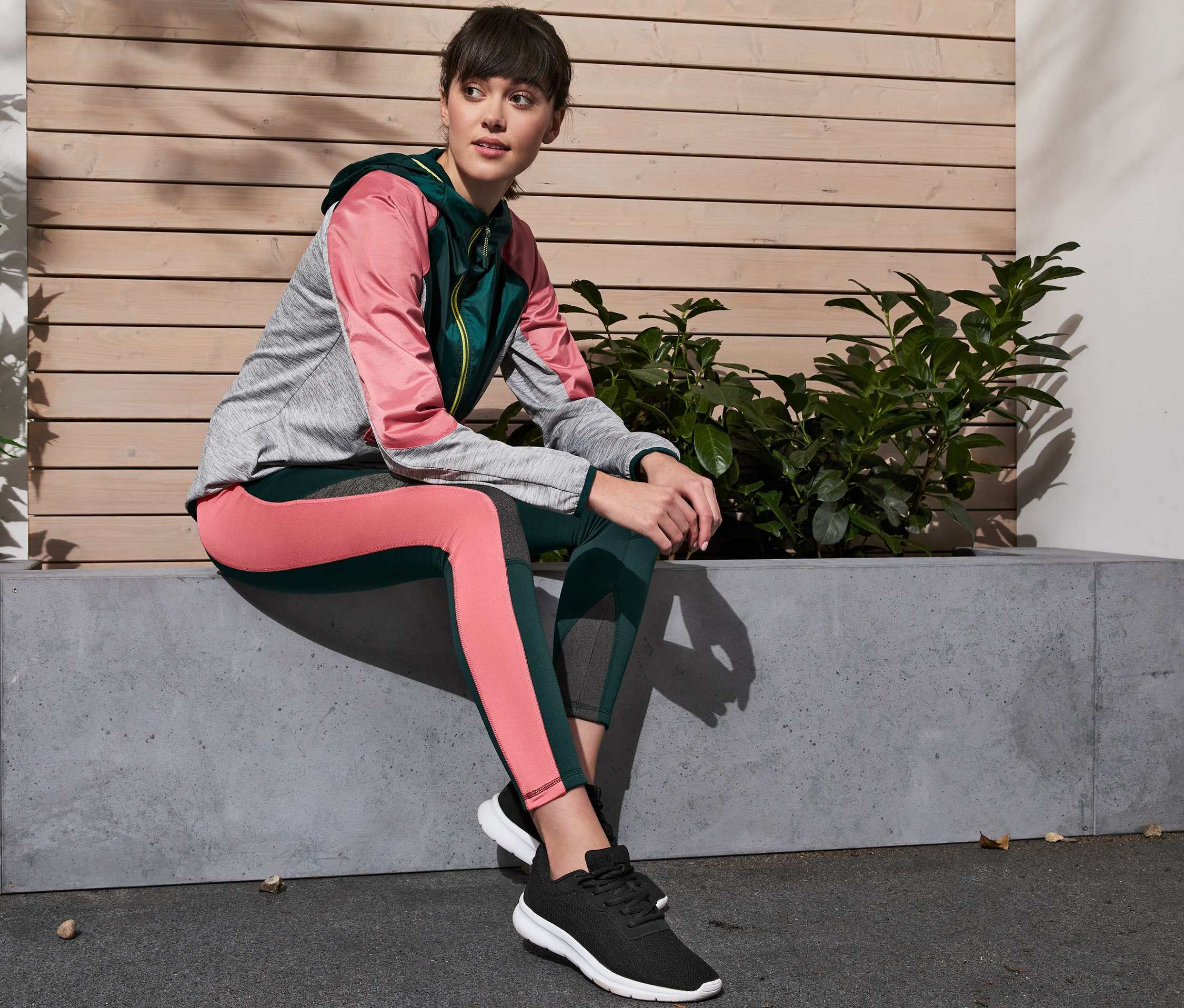 Eine Frau sitzt auf einer Betonbank und trägt eine Thermotight, extrawarm.