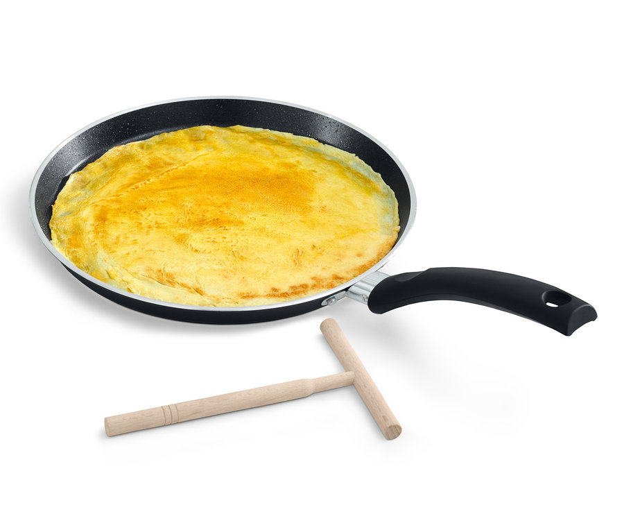 Eine BALLARINI Positano Crêpepfanne aus Aluminium mit einem Crêpe und einem Holzspatel auf einem weißen Hintergrund.