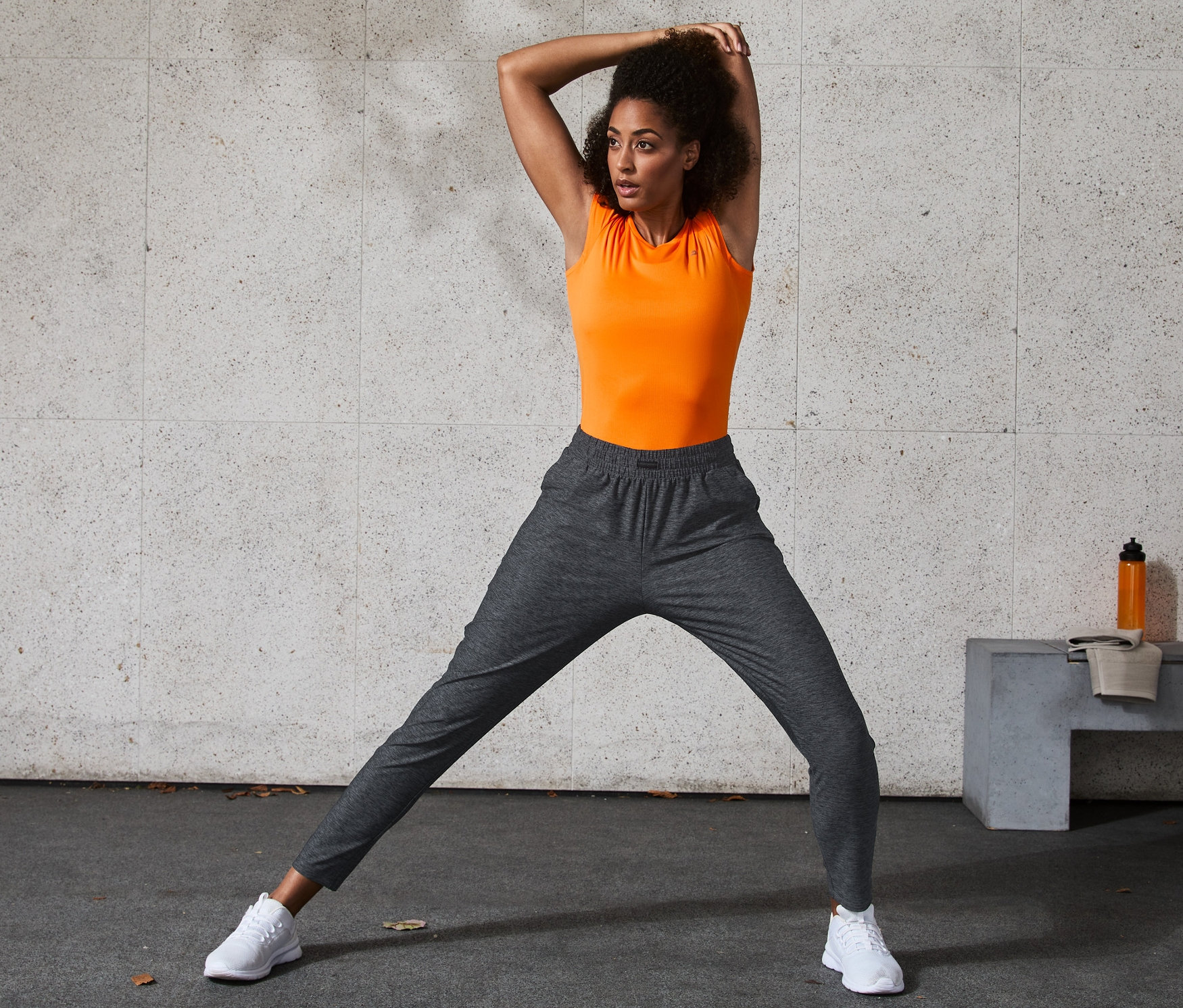 Frau dehnt Beine in Trainingshose.