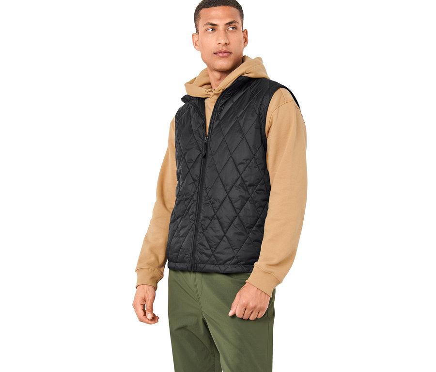Mann trägt eine schwarze Weste einer 3-in-1-Outdoorjacke und olivgrüne Hosen.