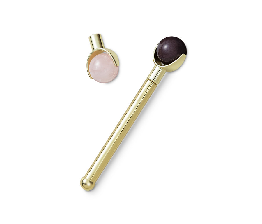 Goldener Edelstein-Gesichtsroller liegt auf einem weißen Hintergrund.