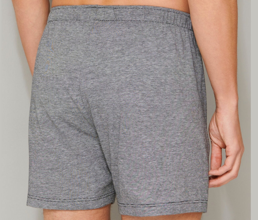 Mann von hinten trägt 2 SCHIESSER Boxershorts aus Baumwolle, schwarz und grau.