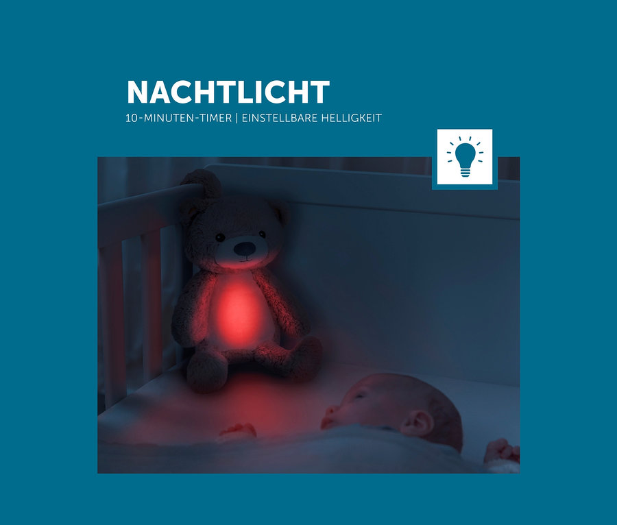 Ein Kind liegt im Kinderbett neben dem Zazu Nachtlicht »Brody der Bär« in Bärenform.