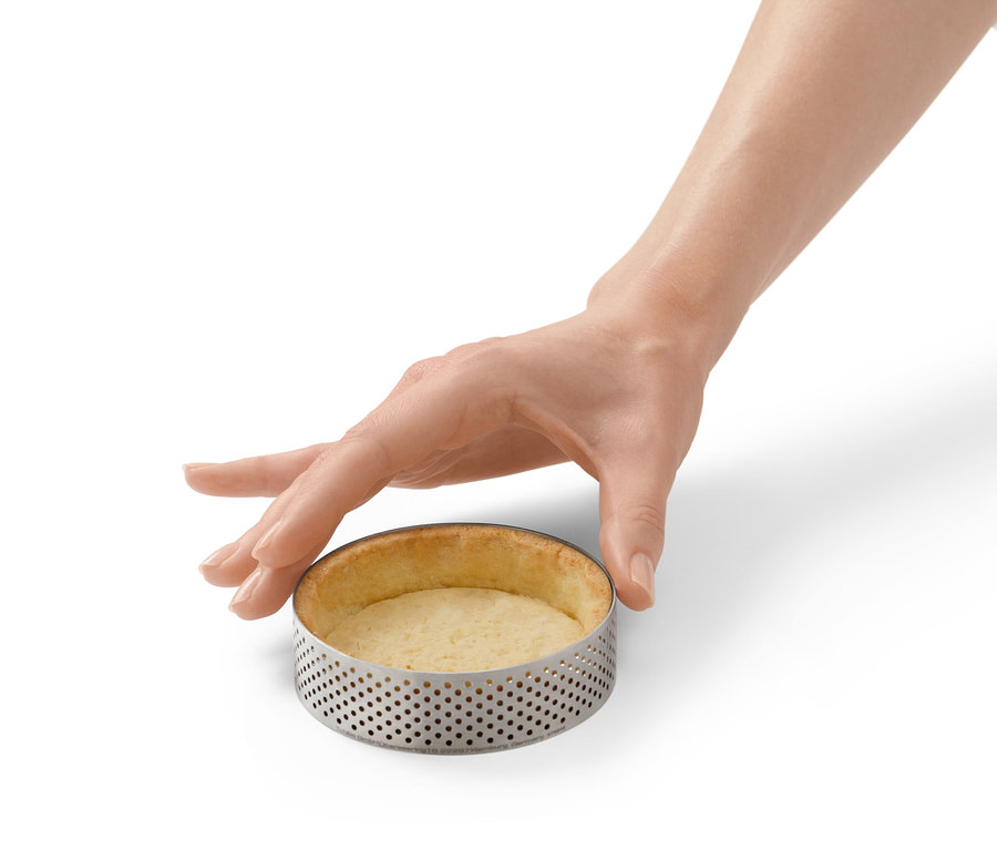 Eine Hand berührt einen Edelstahl-Backring mit gebackenem Teig.