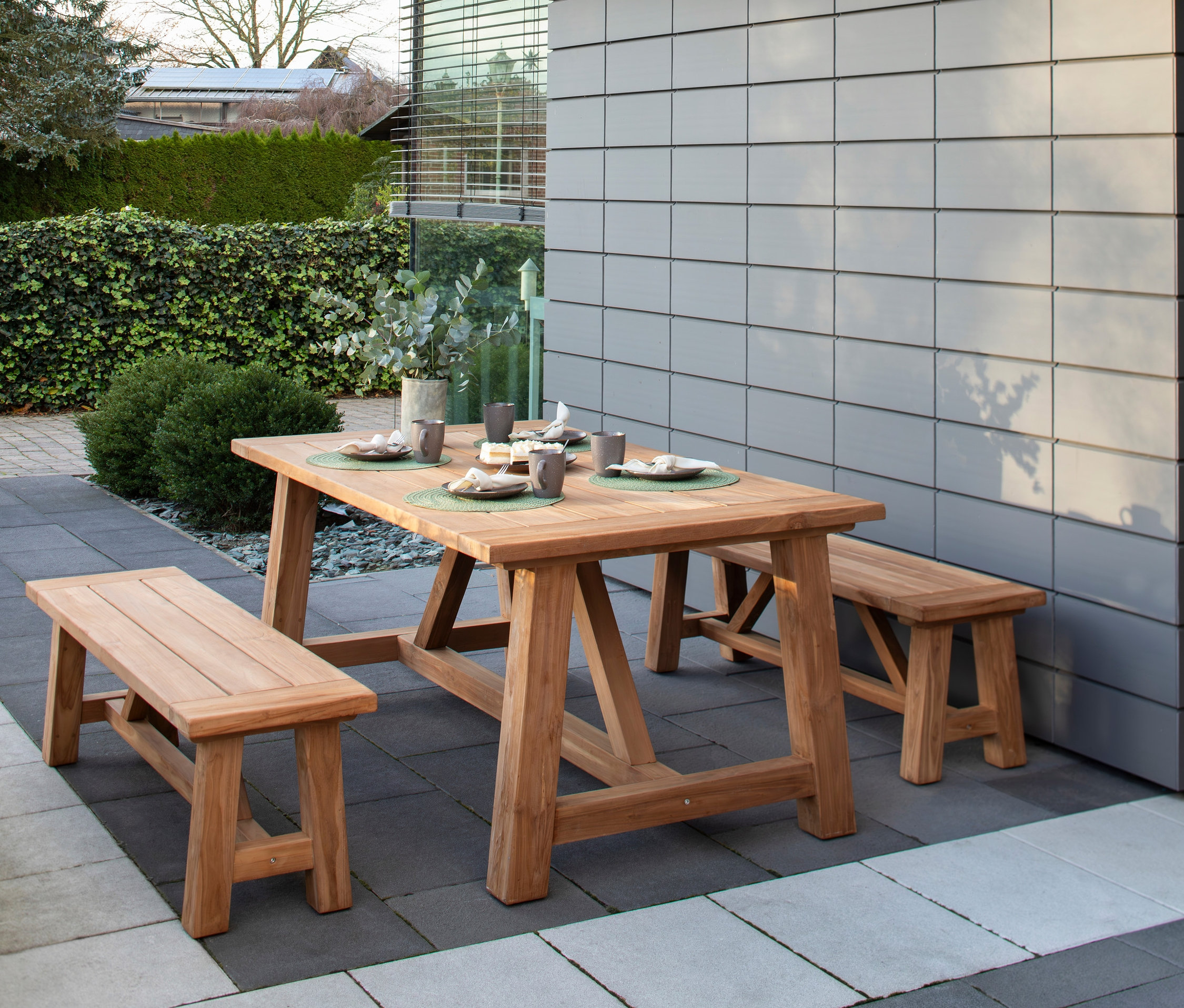 deVries Dining-Set aus Holz auf einer Terrasse mit gedecktem Tisch.