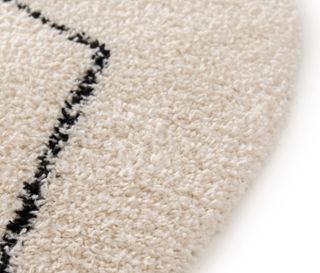 Detailaufnahme eines cremefarbenen runden Nomad Rhombus Line Teppichs mit schwarzem geometrischem Muster.