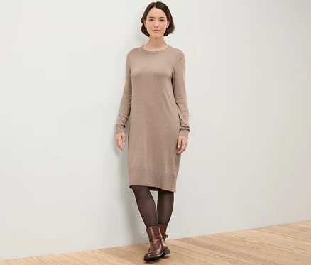 Frau posiert in einem braunen Feinstrickkleid.
