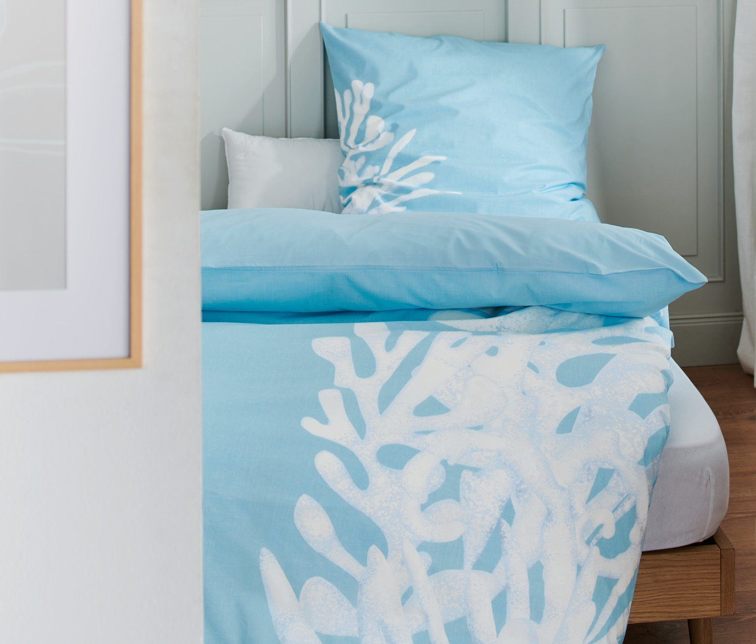 Hellblaue Premium-Baumwoll-Bettwäsche Normalgröße mit weißem Korallenmuster auf einem Bett.