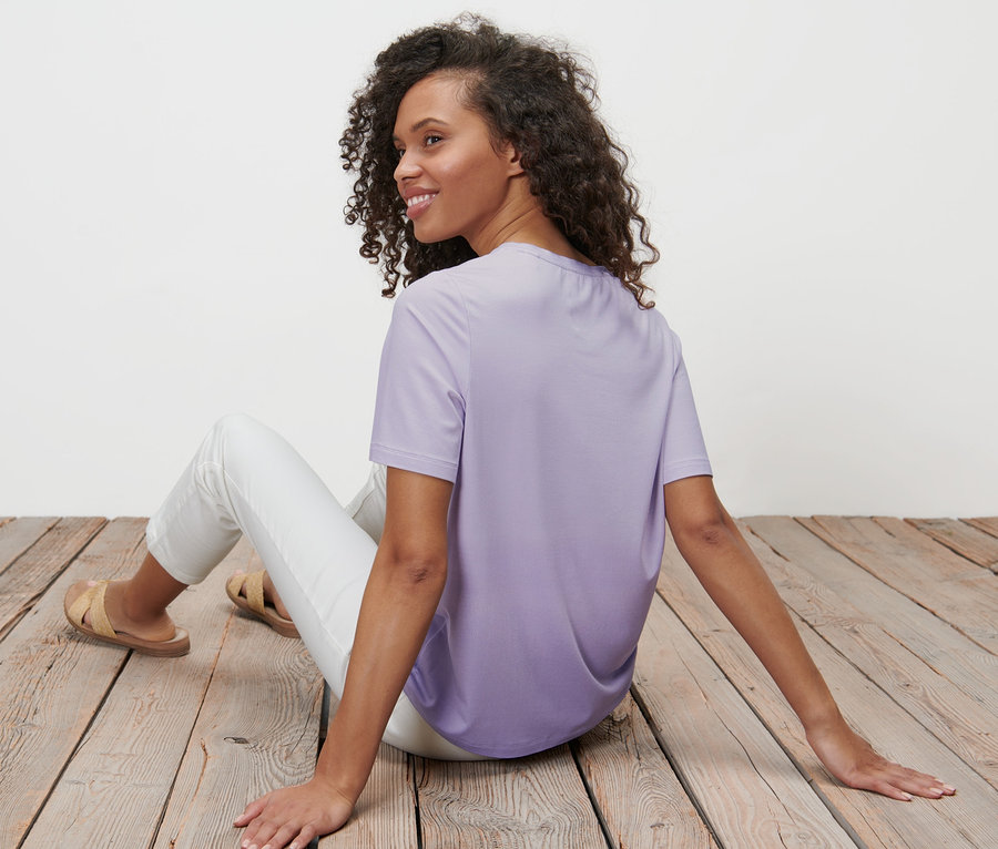 Frau sitzt auf Holzboden und trägt ein Dip-Dye-T-Shirt.