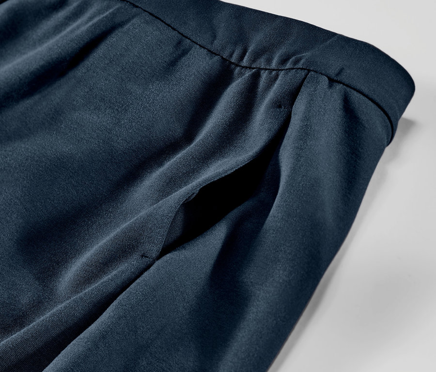 Detailaufnahme einer marineblauen Jerseyhose mit Paspelierung und Taschen.