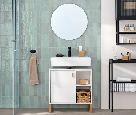 Modernes Badezimmer mit mintgrünen Fliesen. Links eine Duschkabine und Toilette. Rechts ein weißer Waschbeckenunterschrank mit Tür und Seitenfach, darüber ein runder Spiegel «Ameca». Daneben ein schwarzer Wandschrank mit Glastür und eine schwarze schmale Konsole mit Ablageflächen.