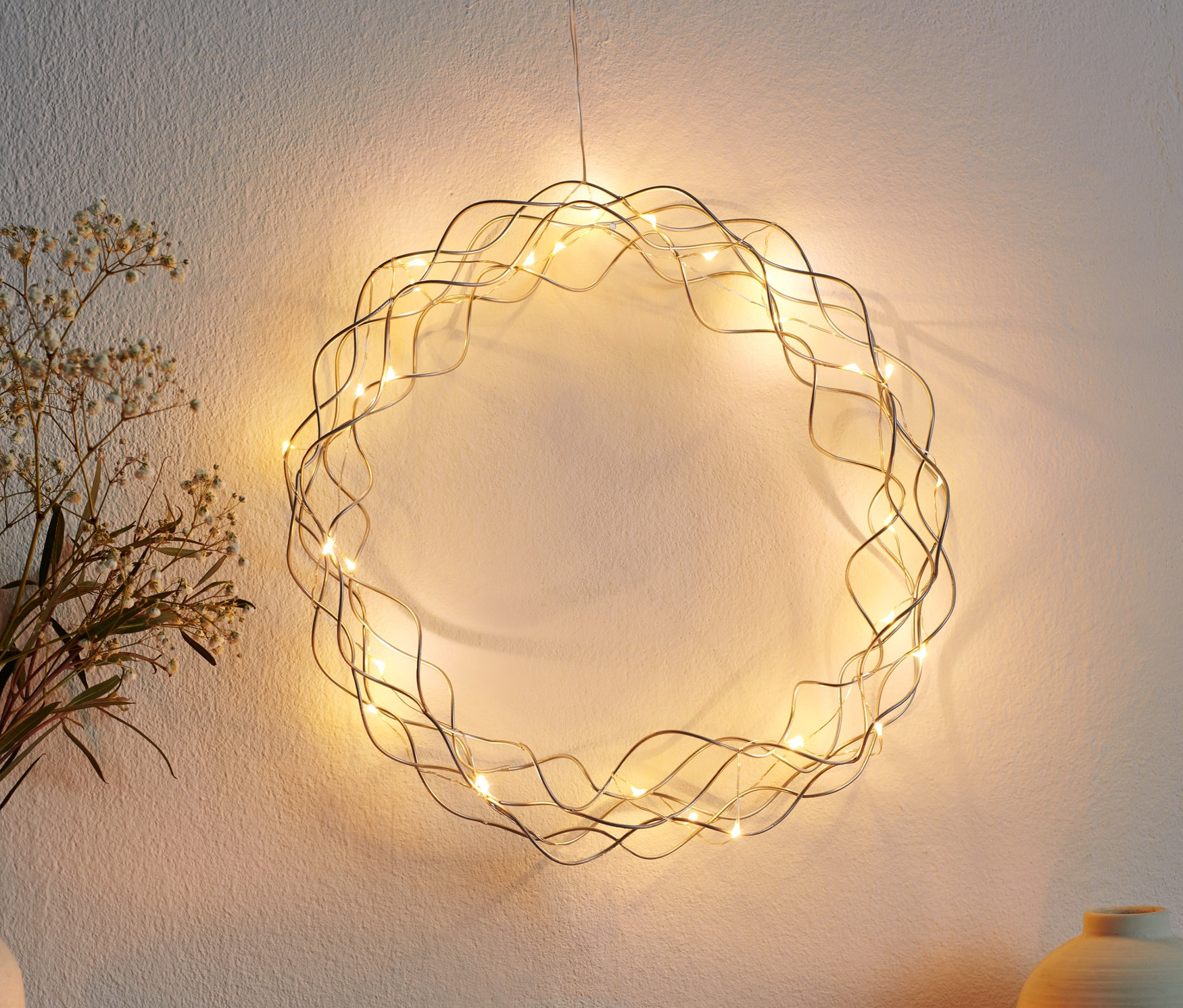 Ein LED-Deko-Kranz hängt an einer Wand.