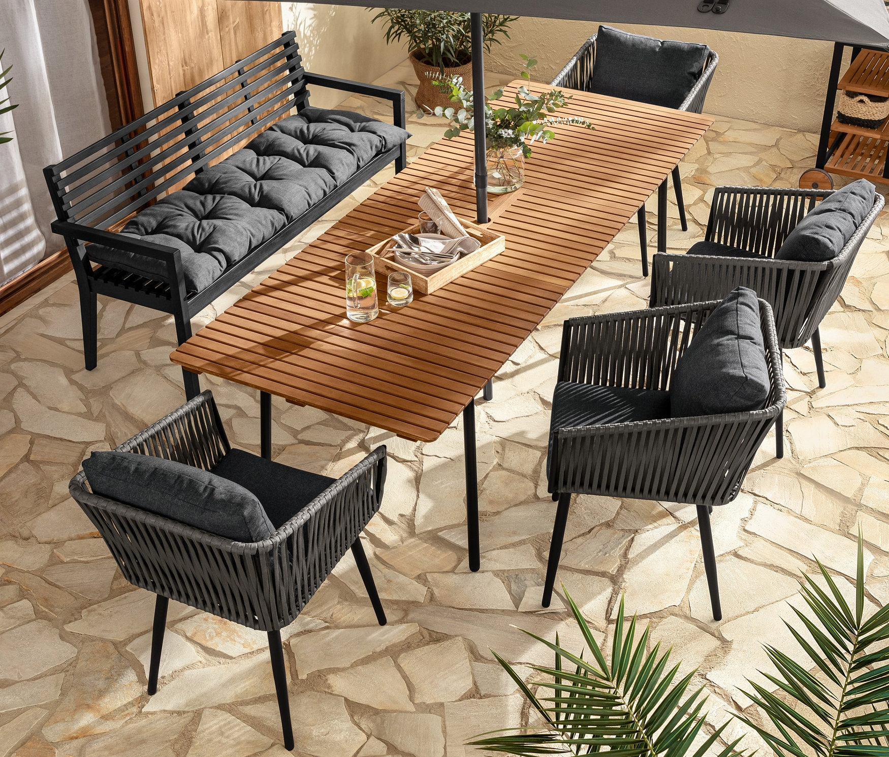 Eine Aussensitzgruppe mit Ausziehtisch »Elin«, Gartenbank mit Armlehne, Dining-Sesseln mit Textilgeflecht und Gartenbank-Auflage.