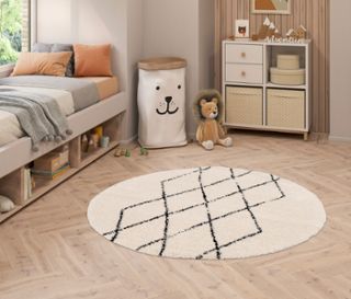 Kinderzimmer mit Bett, Kommode und rundem, beigem Teppich »NOMAD Rhombus Line«, Ø ca. 160 cm, mit schwarzem geometrischem Muster.