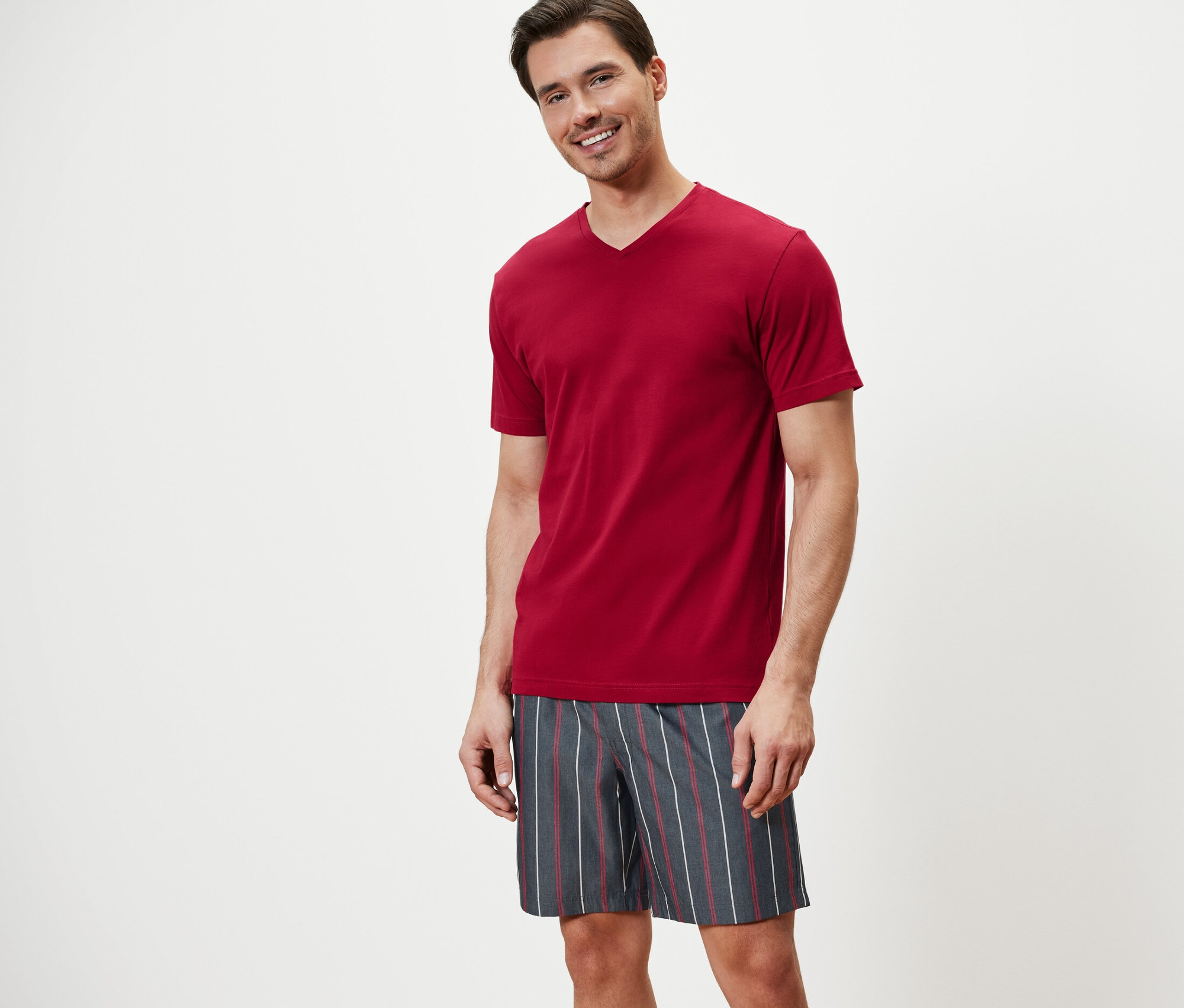 Mann trägt einen Shorty-Pyjama und lächelt.