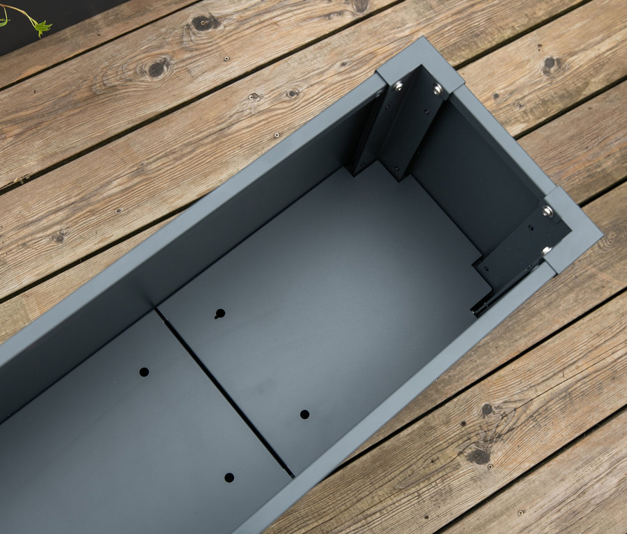 Detailansicht von oben von einem leeren, grauen, rechteckigen Pflanzkasten mit Einlegeboden, ca. 27 cm, auf einem Holzdeck.