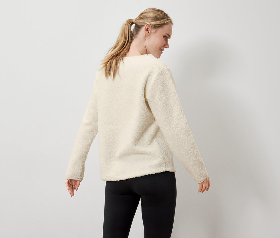 Frau trägt einen cremefarbenen Pullover und schwarze Leggings.