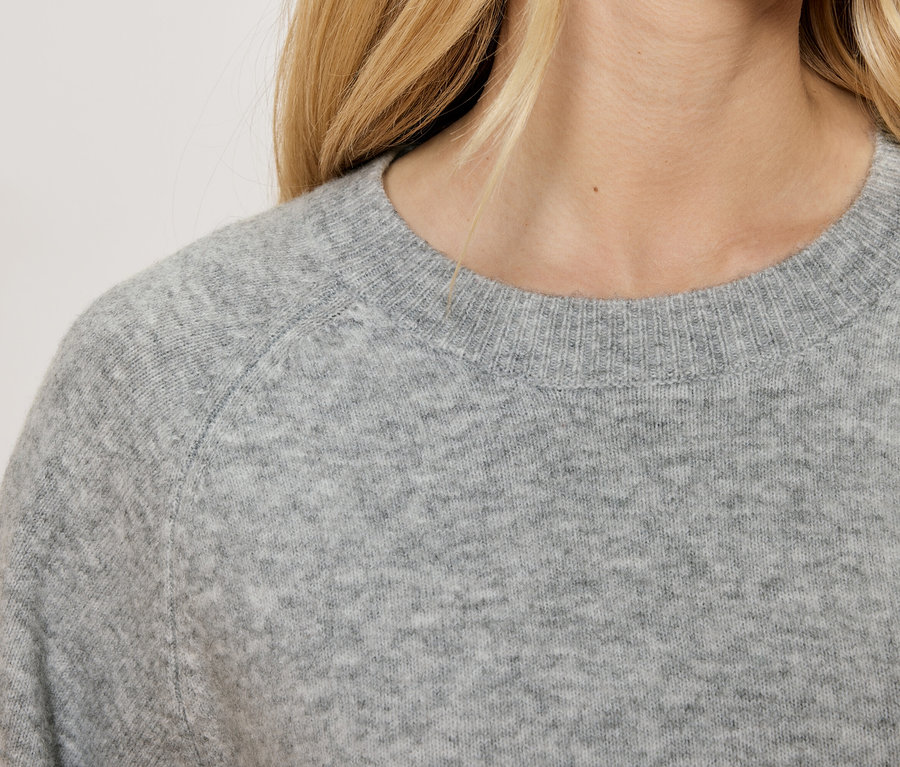 Detailaufnahme eines grauen Damenpullovers mit Rundhalsausschnitt.