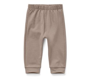 Eine hellbraune Babyhose liegt auf einem weißen Hintergrund.