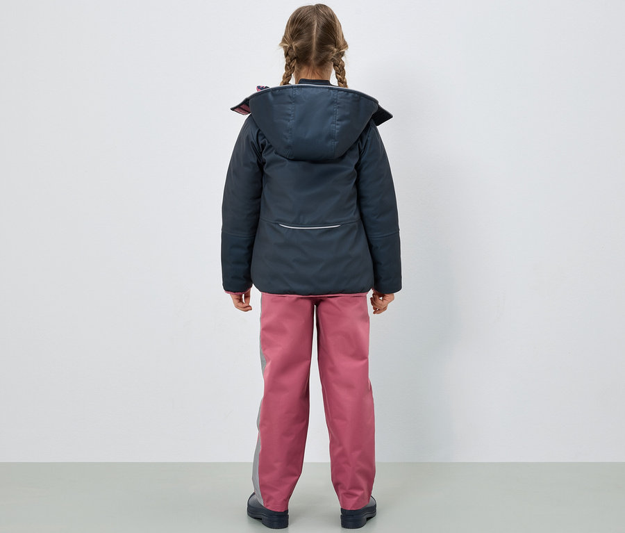 Mädchen von hinten trägt eine dunkelblaue Jacke und eine rosa Kinder-Regenhose.