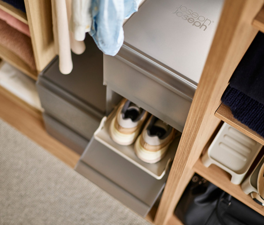 Geöffneter grauer Joseph Joseph Premium-Schuhaufbewahrungsbox in einem Holzregal mit Schuhen darin.