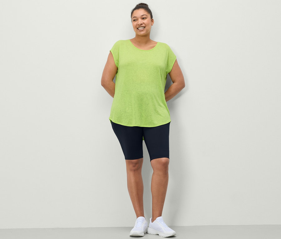 Frau posiert in Sportradler in Dunkelblau und Sportshirt in Lime.