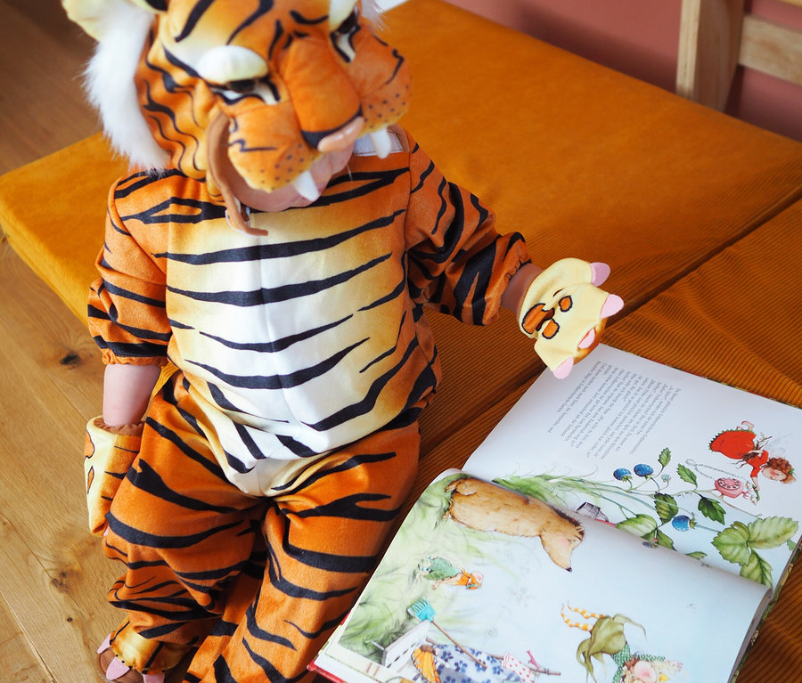 Kind im Tigerkostüm betrachtet ein Bilderbuch und hält ein Spielzeug. small foot Kostüm »Tiger«