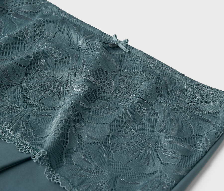 Nahaufnahme von blaugrüner Spitze mit einer Schleife im oberen Bereich.