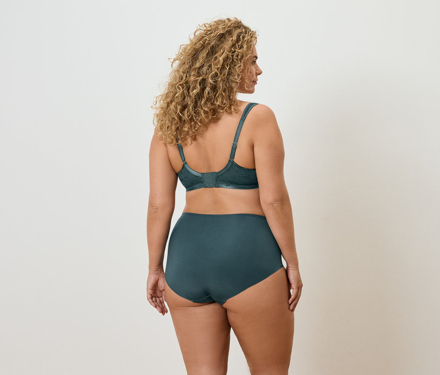 Rückansicht einer Frau mit lockigem Haar, die einen grünen BH und Höschen trägt.