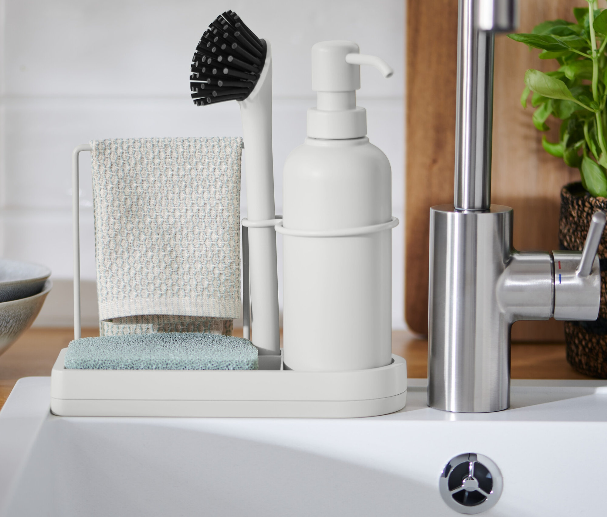 Spülbecken-Organizer mit Bürste, Lappen und Seifenspender neben Spülbecken.