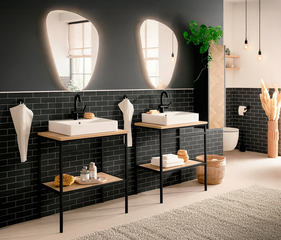 Badezimmer mit zwei Waschbecken auf Waschtischen, zwei beleuchteten Spiegeln und schwarzen Fliesen.