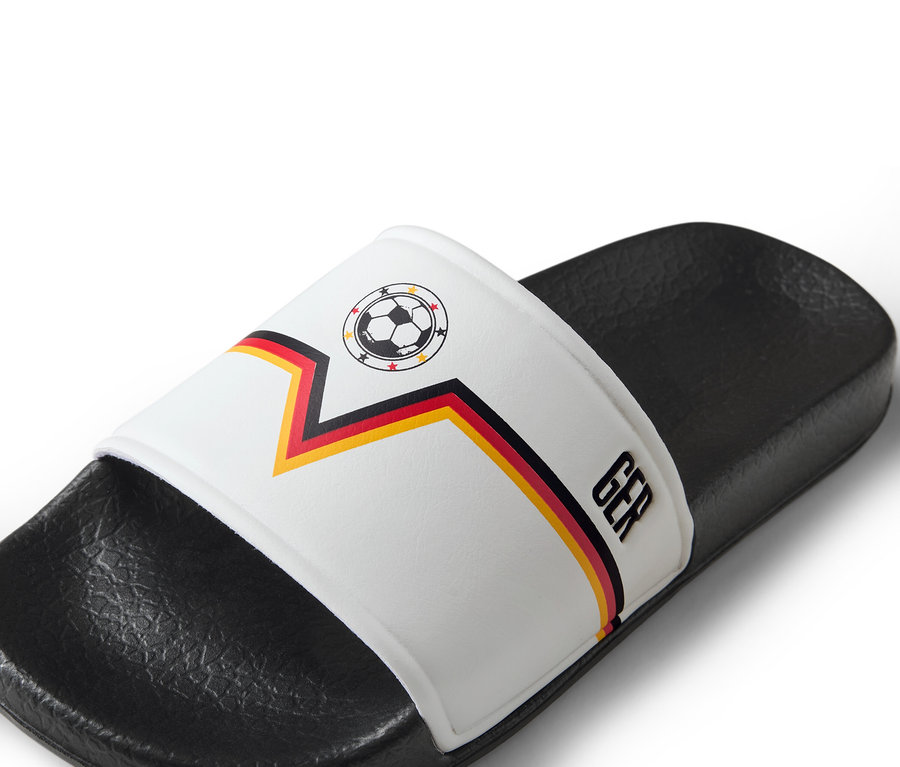 Nahaufnahme eines einzelnen weißen Slippers mit einem deutschen Fußball-Design.