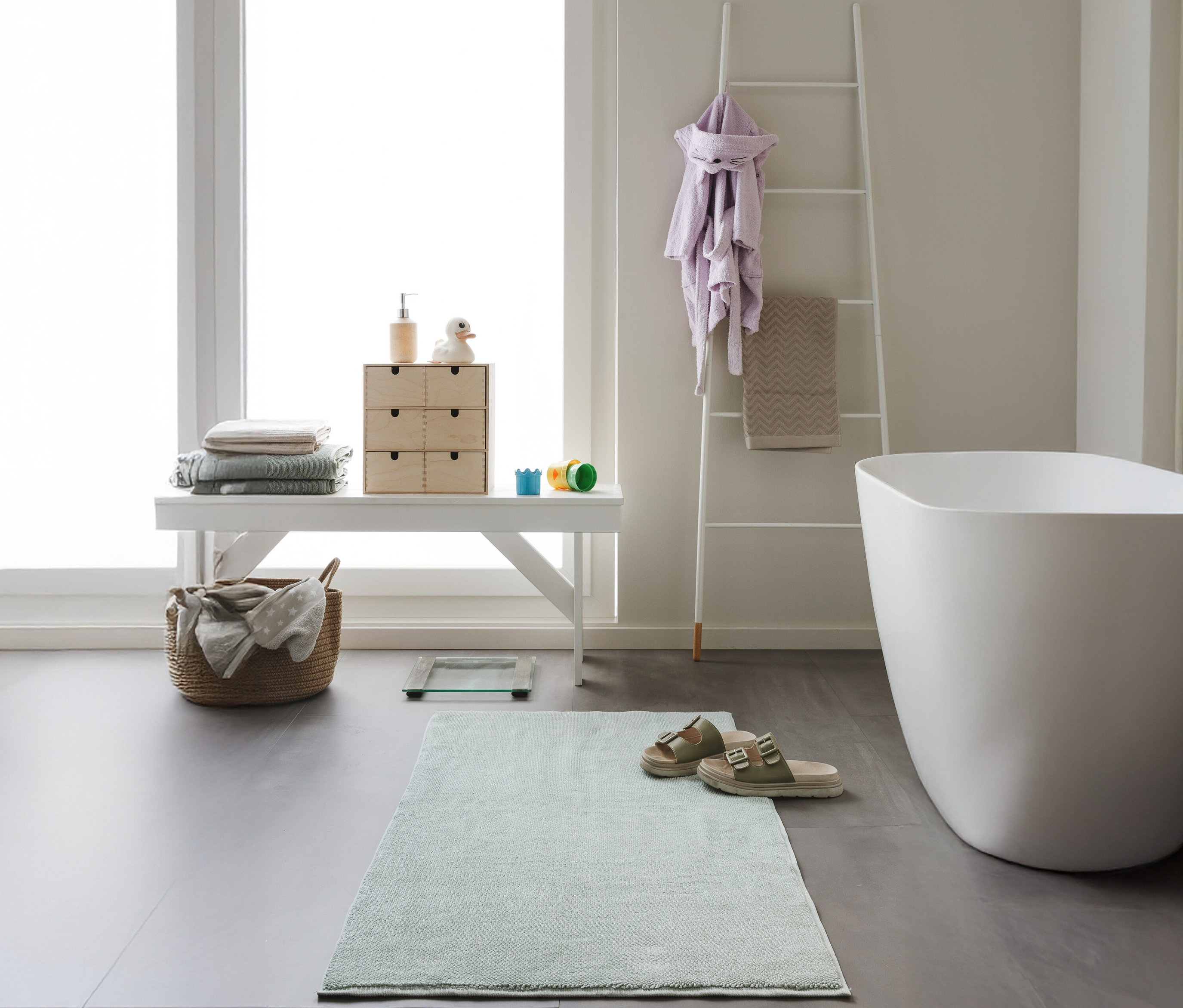 Badezimmer mit weißer Bank, Badewanne und mintfarbener benuta Badematte »Ole« 50 x 80 cm.