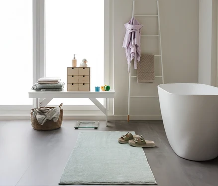 Badezimmer mit weißer Bank, Badewanne und mintfarbener benuta Badematte »Ole« 50 x 80 cm.