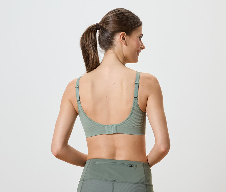 Rückansicht einer Frau mit Pferdeschwanz, die einen grünen Sport-BH und Leggings trägt.