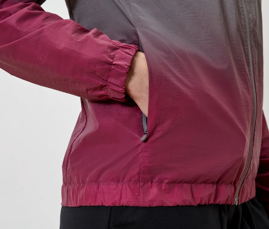 Person mit Hand in der Tasche einer weinrot-grauen Jacke mit Reißverschluss.