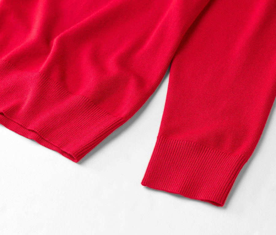 Detailansicht eines roten Pullovers auf weißem Grund.