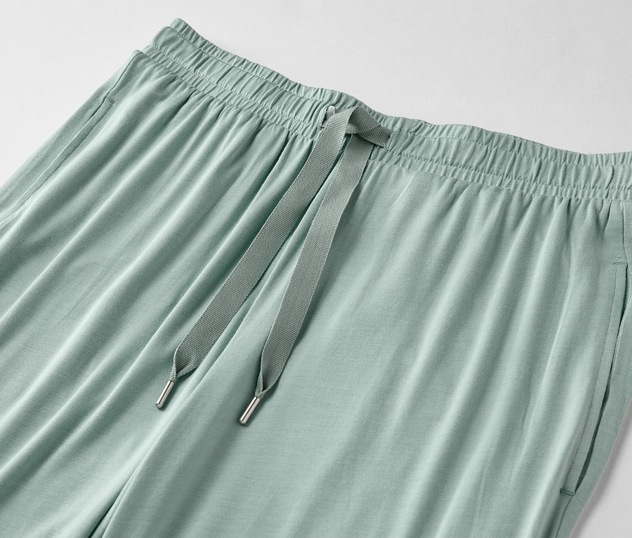 Nahaufnahme einer hellgrünen Hose mit Kordelzug und Taschen.